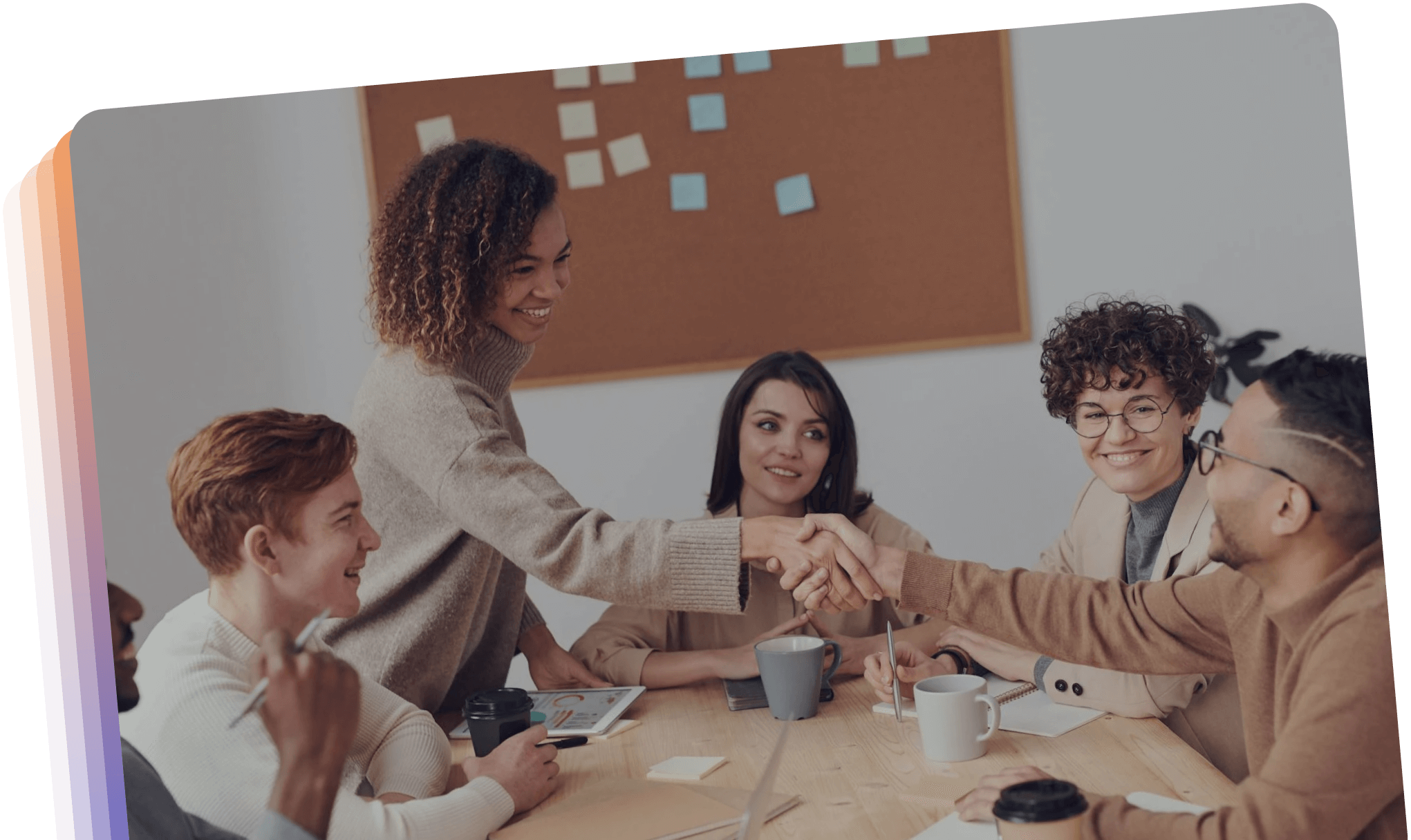 A diverse group of individuals shaking hands around a conference table, symbolizing collaboration and agreement.