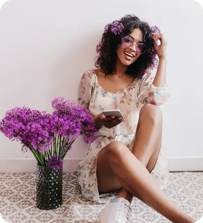 A woman sitting on the floor surrounded by vibrant purple flowers, creating a serene and colorful atmosphere.