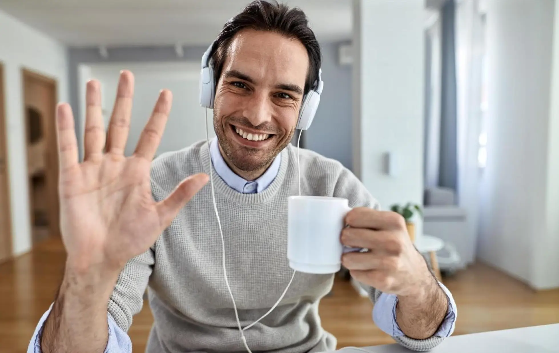A man listens to music through headphones while holding a cup of coffee, embodying a moment of leisure.