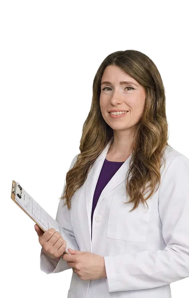 A female doctor stands confidently, holding a clipboard and reviewing patient information in a clinical setting.